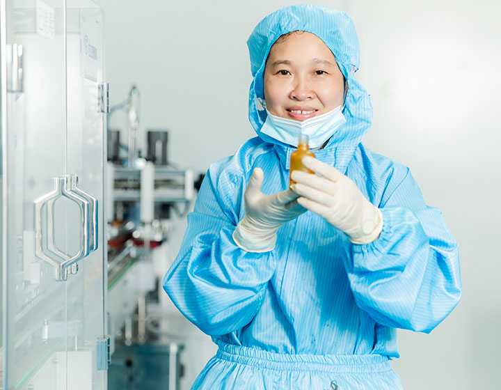 a smiling worker with a bottle on her hand