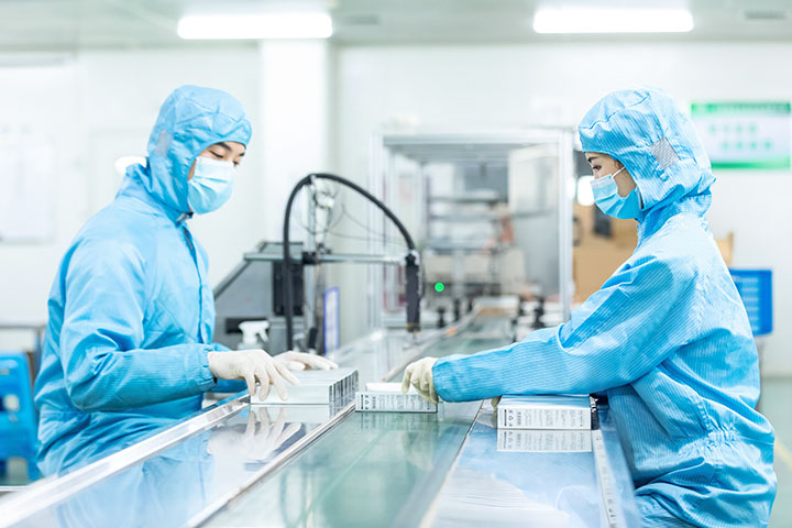 2 workers in anti bacteria uniform are checking the finished essential oils on the conveyor