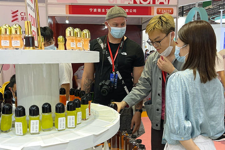 2 foreign purchasers in front of a shelf full of essential oil samples